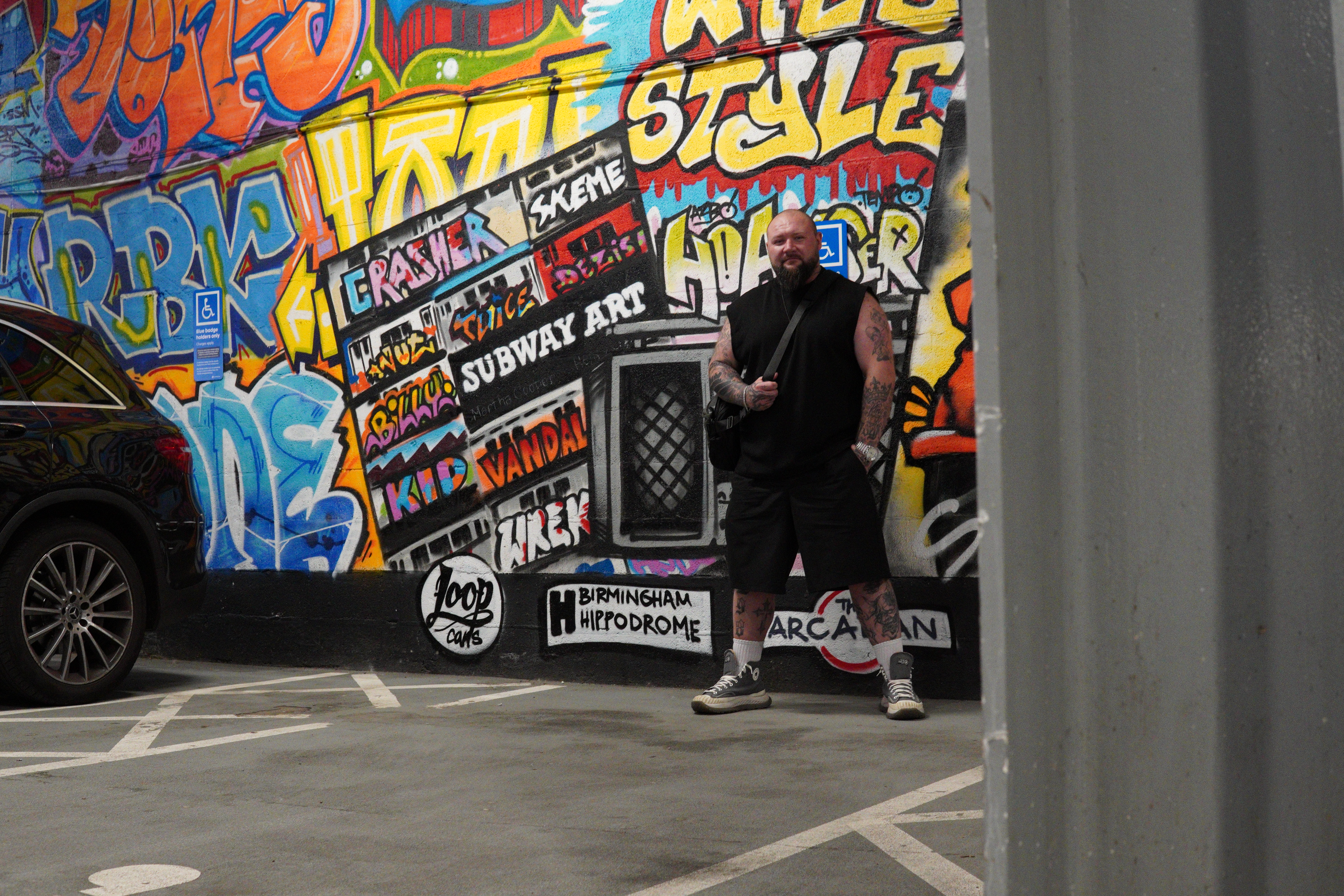 Bartosz Musiol standing in front of a graffiti wall