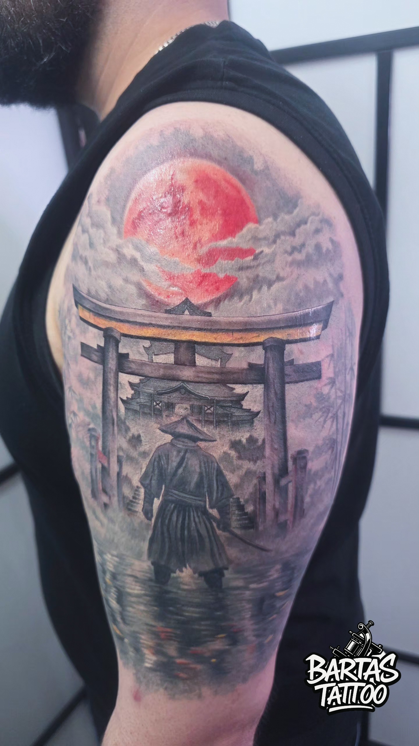 Japanese samurai and torii gate tattoo on an upper arm